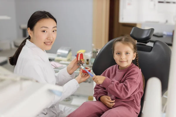Szczęśliwy Uśmiechnięty Azjatycki Dentysta Mówi Małej Dziewczynce Jak Myć Zęby — Zdjęcie stockowe