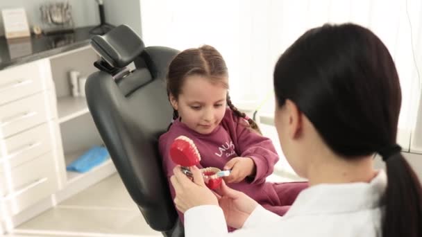 快乐的笑着的亚裔女牙医告诉小女孩如何在人造下巴模型上刷牙 防止蛀牙 儿科牙科 乳牙卫生概念 — 图库视频影像