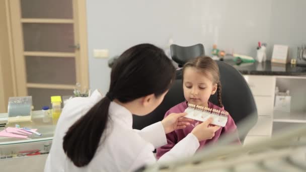 牙齿色调调色板 口腔学家牙齿矫正牙医选择病人可爱的学龄前小女孩牙齿的颜色在诊所美白 — 图库视频影像