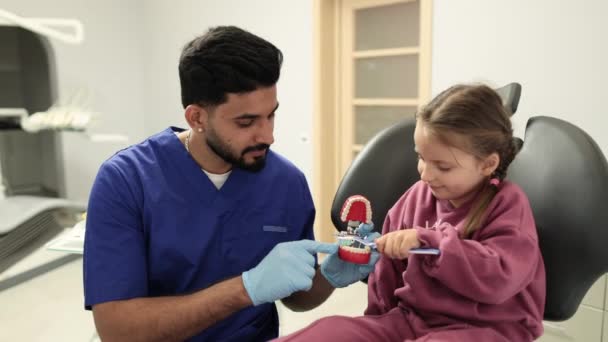 Dentista Masculino Confiante Feliz Diz Menina Pequena Como Escovar Dentes — Vídeo de Stock