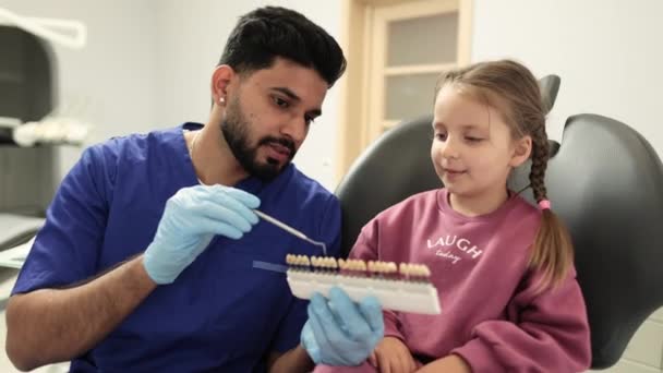 医生填充物主观感知色彩的视觉方法 有自信的男牙 检查并选择年轻的高加索女孩的牙齿颜色 — 图库视频影像