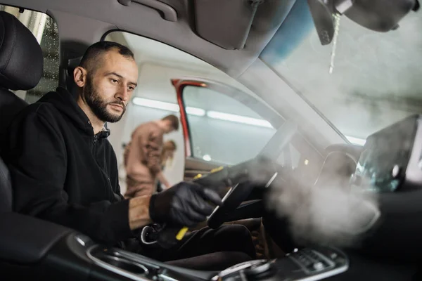 자동차용 미용실을 세척제로 확신하는 직업적 남자가 세척제를 사용하여 자동차 내부를 — 스톡 사진