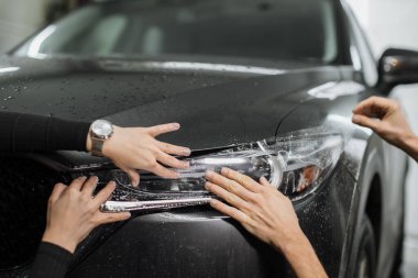 Ön fardaki PPF kurulum işlemine yakın. PPF, boyayı çiziklerden ve taş parçalarından koruyan bir boya koruma filmidir. Gardiyan, koruma, araba, yeni iş kavramı.