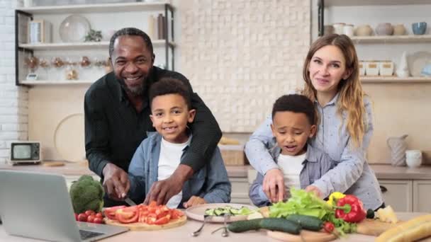 小さな未就学児の男の子を教える幸せな若い両親一緒に愛するお母さん お父さん 小さな息子の子供たちが一緒に夕食を調理する昼食のためのサラダを準備ナイフで野菜を切る — ストック動画