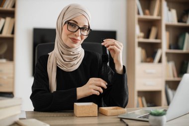 Arabian female blogger sharing her feedback about modern gadget with her subscribers. Muslim woman doing live stream while unpacking box with new smart watch.