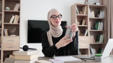 Accounting, taxes and finances concept - young confident muslim woman with papers counting money at modern office, concept of counting money.