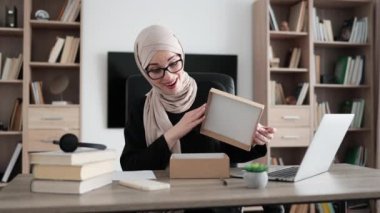 Arabian female blogger sharing her feedback about modern gadget with her subscribers. Muslim woman doing live stream while unpacking box with new smart phone.