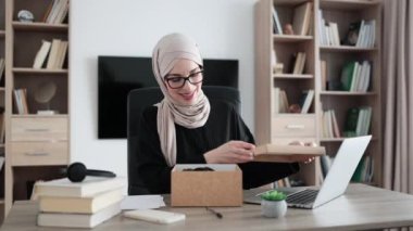 Arabian female blogger sharing her feedback about modern gadget with her subscribers. Muslim woman doing live stream while unpacking box with new headphones.