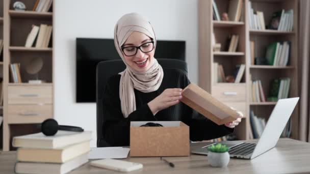 Muslim Woman Doing Live Stream While Unpacking Box New Headphones — Stockvideo