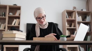 Arabian female blogger sharing her feedback about modern gadget with her subscribers. Muslim woman doing live stream while unpacking box with new tablet.