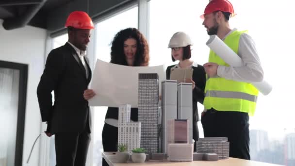 Multicultural Workers Reflective Vest Helmets Blueprint Using City Model Architects — Vídeo de Stock