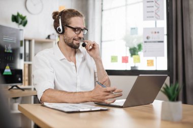 Beyaz gömlekli beyaz erkek ofis yöneticisi internette çalışırken kablosuz dizüstü bilgisayar kullanarak finansal rapor yazıyor. Çevrimiçi iletişim kavramı.