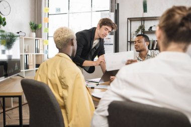 Group of competent multiracial male economists gathering at office room for discussing financial situation of company. Cooperation for common succes. Modern gadgets for work.