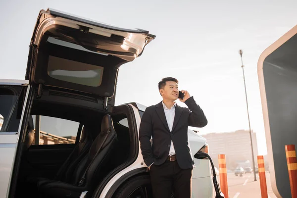 Framgångsrik Asiatisk Affärsman Som Har Mobil Konversation Väntan Elbil För — Stockfoto