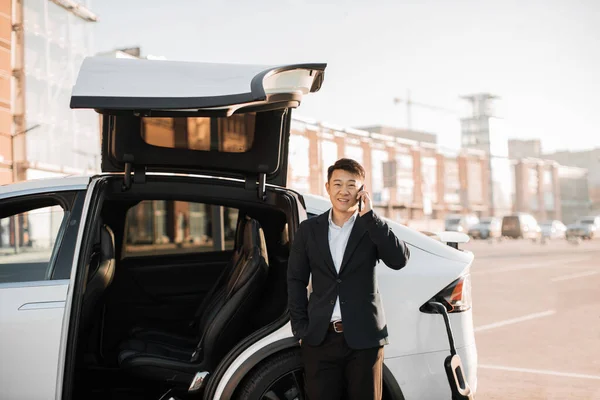 Framgångsrik Asiatisk Affärsman Som Har Mobil Konversation Väntan Elbil För — Stockfoto