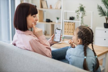 Güzel, genç bir anne, küçük kızına satış sezonunda online butiğe bakarken kozmetik ürünlerini seçmenin temel kurallarını öğretiyor. Mutlu bir aile akıllı telefondan alışveriş yaparken eğleniyor..