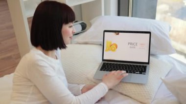 Güzel genç bir kadın evde rahat rahat rahatlıyor ve online alışveriş için modern dizüstü bilgisayar kullanıyor. Kafkasyalı esmer, indirimde fast food sipariş ediyor. Ekrana odaklan.