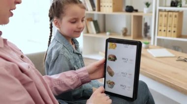 Esmer, beyaz kadınlar dairede kalırken internetten fast food dağıtım sitesinde dijital tablet kullanarak sörf yapıyorlar. Güzel kadın ve tatlı kız içerideki abur cuburlarda indirimleri kontrol ediyor..