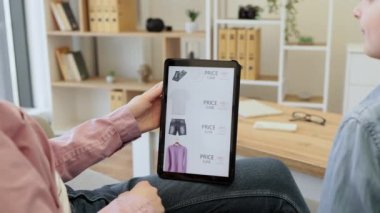 Ekranda indirimli indirimli giyim mağazaları ile dijital tableti kapatın. Anne ve çocuk dairede takılıp elektronik aletlerle internet alışverişi yapıyorlar..