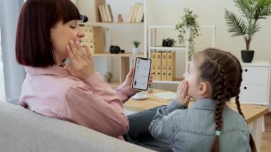 Güzel, genç bir anne, küçük kızına satış sezonunda online butiğe bakarken kozmetik ürünlerini seçmenin temel kurallarını öğretiyor. Mutlu bir aile akıllı telefondan alışveriş yaparken eğleniyor..