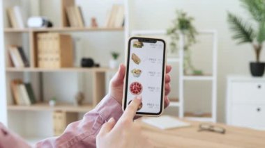 Evde akıllı telefon tutan, internetten fast food alan kadın ve kız ellerini yakın çekimde. Anne ve kızı e-ticaret için cep telefonu kullanırken birlikte vakit geçiriyorlar..