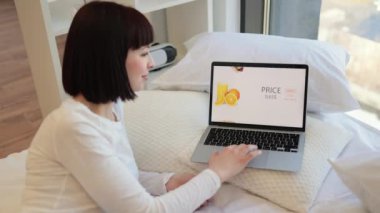 Güzel genç bir kadın evde rahat rahat rahatlıyor ve online alışveriş için modern dizüstü bilgisayar kullanıyor. Kafkasyalı esmer, indirimde fast food sipariş ediyor. Ekrana odaklan.