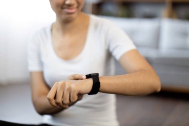 Genç, çok ırklı bir kadın dairede yerde dinlenirken spor salonuna bakıyor. Neşeli zinde bir kadın, evden çıkarken kalp atışlarını kontrol ediyor..