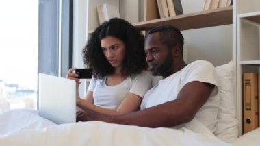Evde internet bankacılığı için kredi kartı kullanırken çok ırklı ailelerin sabahlarını dizüstü bilgisayarla yatakta geçirmesine bayılıyorum. Mevcut başvuruda çevrimiçi ödeme işlemleri yapan romantik ortaklar.