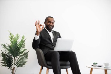 Resmi olarak çalışan çalışkan Afrikalı çalışanlar, ofisteki kablosuz bilgisayarda imzayı gösteren modern minimalist tasarımla yazarken kameraya içtenlikle gülümserken giyerler. İnsanlar, iş ve teknoloji kavramı.