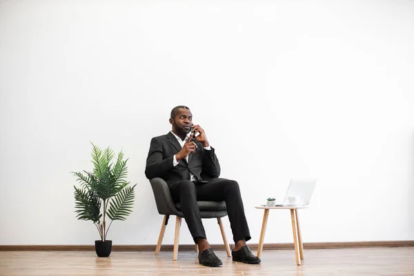 オフィスセンターで働いている間 ビジネスでアフリカ人男性が現代のスマートフォンで話しているのを確信しています 遠隔地のパートナーとの作業上の問題を解決する集中雇用主 — ストック写真