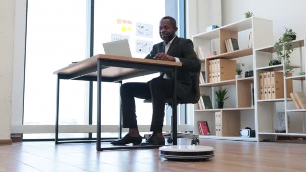 有组织的多种族员工坐在办公室桌上 通过遥控打开机器人真空吸尘器 通过日常吸尘提供健康工作环境的专业企业家 — 图库视频影像