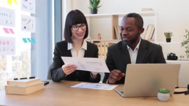 Kendine güvenen, çok ırklı takım elbiseli bir yönetici ve modern dizüstü bilgisayarla video görüşmesi yapan beyaz bir asistan. Verimli profesyoneller kullanılabilir uygulama kullanarak müşterilerle çevrimiçi sohbet ediyorlar.