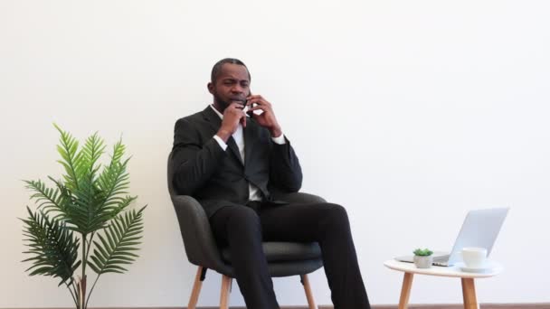 Африканець Діловому Костюмі Сидить Кріслі Смартфоном Руках Задумливо Дивиться Вгору — стокове відео
