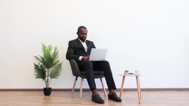 사무실에 앉아서 현대적 노트북을 만드는 아프리카 미국인에게 초점을 맞추었습니다 정장을 — 비디오
