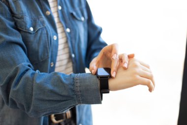 İş yerinde pencerenin yanında dururken kadın ofis çalışanı bileğine dokunuyor. İş için modern kablosuz cihaz. Elektronik aksesuar kavramı.