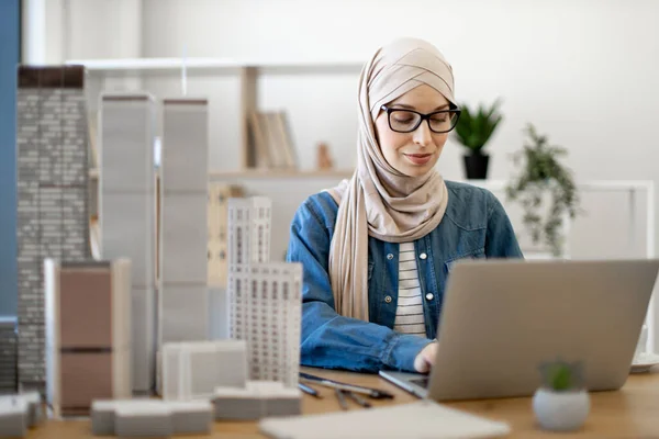 Összpontosított Muszlim Hidzsábban Gépel Hordozható Számítógépen Irodai Asztalnál Épületmodellekkel Tapasztalt — Stock Fotó