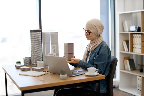 Vonzó Arab Üzletasszony Hidzsábot Visel Többszintes Épületmodellt Tart Miközben Íróasztalnál — Stock Fotó