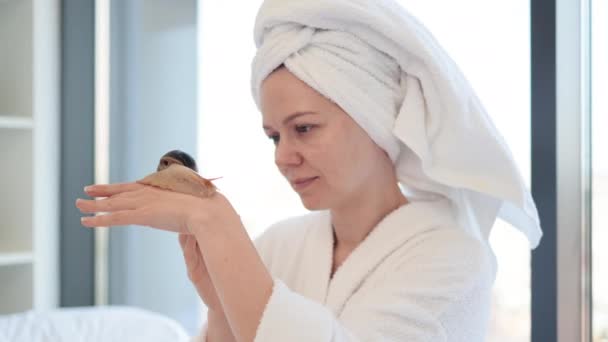 迷人的高加索女人头戴浴巾 看着一只大蜗牛从一只手滑到另一只手背在房间里 漂亮女人周末喜欢用可爱的动物做美容疗法 — 图库视频影像