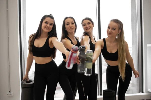 Mujeres Sonrientes Ropa Yoga Posando Con Botellas Deportivas Unidas Mientras —  Fotos de Stock