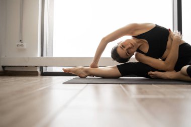 Güzel genç bir kadının havadar fitness merkezinde yoga yan kıvrımları esnetiyordu. Arka planda panoramik pencereler var. Sağlıklı yaşam tarzları ve refah kavramı.