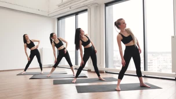 在宽敞的演播室里 身穿黑色运动服的漂亮纤细女子走进三角斗篷 放松瑜伽练习者在练习运动时增加整体稳定性 — 图库视频影像