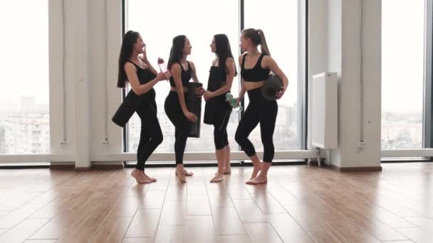 一群身穿运动服的年轻女运动员站在健身工作室的全景窗前 带着橡胶垫子和运动瓶 同事瑜伽同伴在室内全身运动后休息 — 图库视频影像