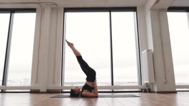 Dar bluzlu çekici esmer kadın ve spor salonunun çalışma odasında, Omuz Duruşu Pozu 'nda dengede duran yoga pantolonu. Sıska kadın Sarvangasana kullanarak vücut gücünü arttırıyor..