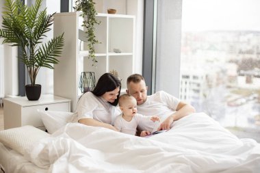 Güzel bir kadın yatak odasındaki yorganın altında dinlenirken küçük kız ve özenli bir erkekle birlikte kelimesiz resimlere bakıyor. Düşünceli ebeveynler ilgili çocuğa hafta sonları hikayeler anlatıyor..