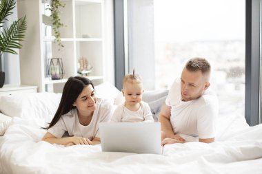 Genç, beyaz anne ve babalar her gün evde taşınabilir bilgisayarın önünde küçük tatlı kızlarıyla yatakta yatıyorlar. Güneşli bir günde internetten film izleyen üç kişilik sevgi dolu bir aile..