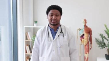 Dost canlısı, laboratuvar önlüklü yetişkin erkek modern hastanenin profesyonel ofisinde kalırken iyi bir hareket gösteriyor. Gülümseyen doktor klinik geçmişinde yeni tedaviye onay veriyor.