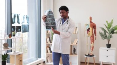 Beyaz önlük ve steteskop giyen çok ırklı bir yetişkin. Doktorun ofisinde çalışırken beyin taraması yapıyor. Doğru tedavi planı üzerinde karar veren dikkatli sağlık uygulayıcısı.