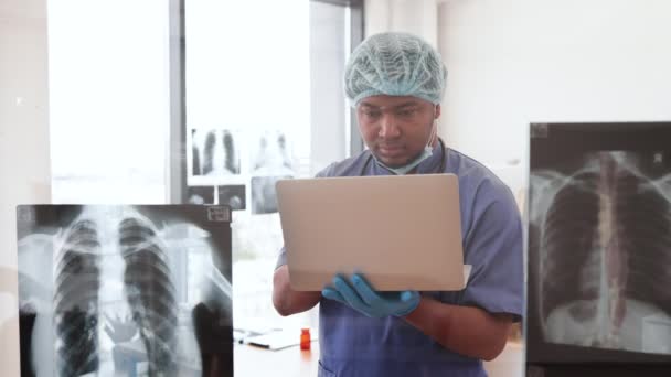 Skupiony Wielonarodowy Mężczyzna Medycznym Fartuchu Czapce Masce Trzymający Komputer Stojąc — Wideo stockowe