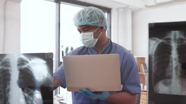 Focused Multiethnic Male Medical Scrubs Cap Mask Holding Computer While — Stock Video