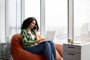 Ofis dosya deposunun yanındaki yumuşak koltukta bilgisayarla internet üzerinden konuşurken çok ırklı bir kadın telefonda konuşuyor. Günlük kıyafet giyen şirket çalışanı müşterilerle internet üzerinden iletişim kuruyor..